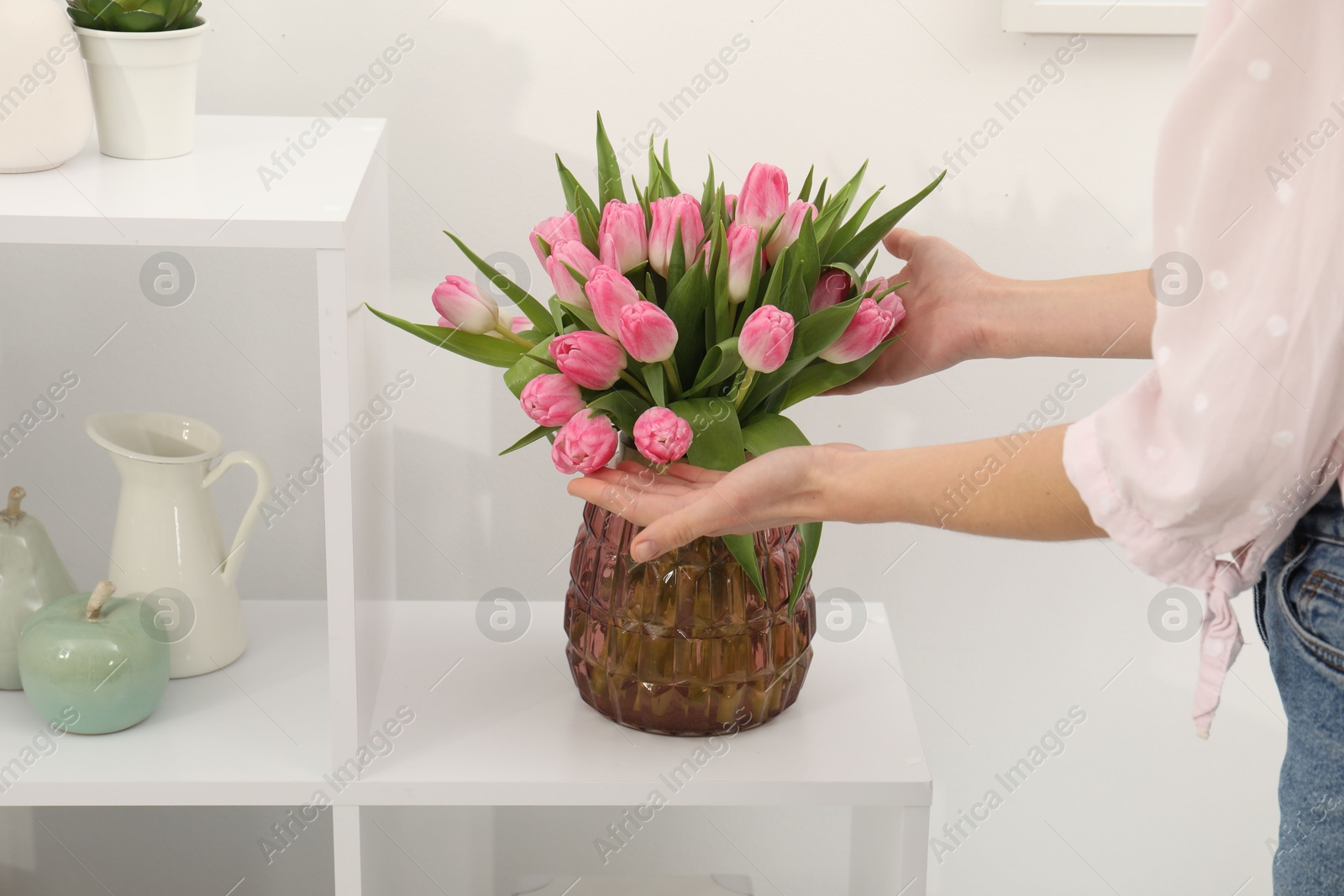 Photo of Woman with bouquet of beautiful tulips near shelving unit indoors, closeup