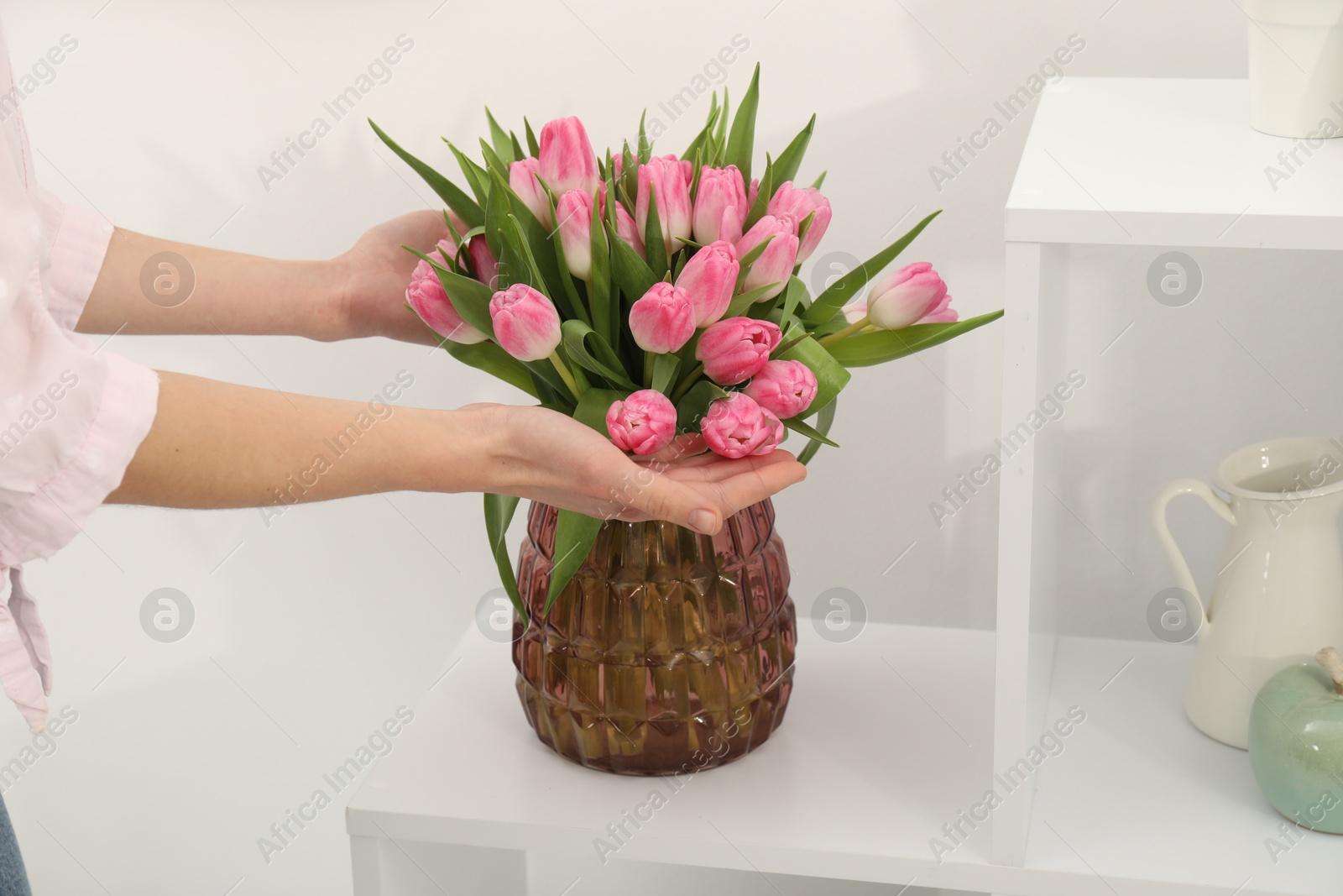 Photo of Woman with bouquet of beautiful tulips near shelving unit indoors, closeup