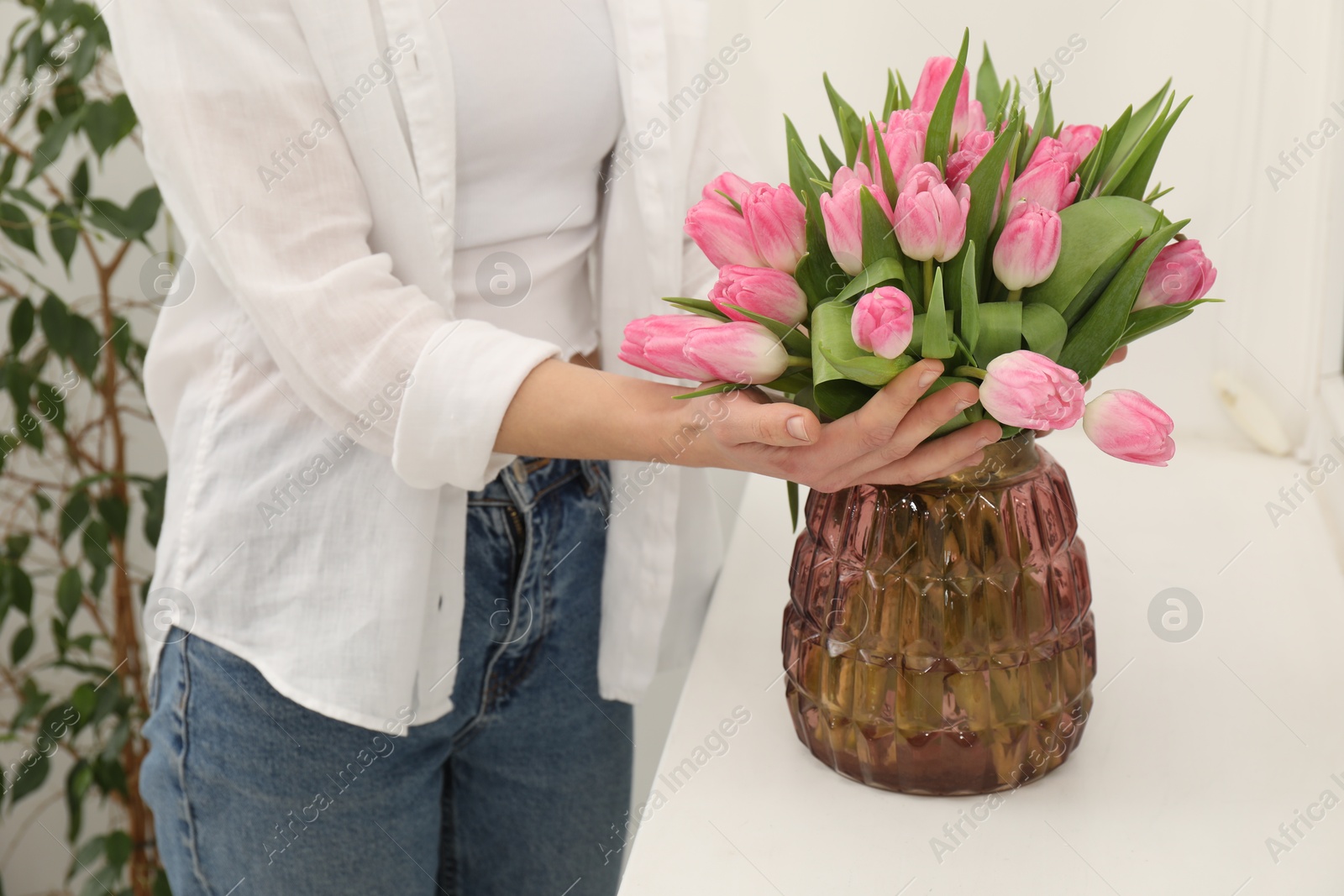 Photo of Woman with bouquet of beautiful tulips near window sill indoors, closeup