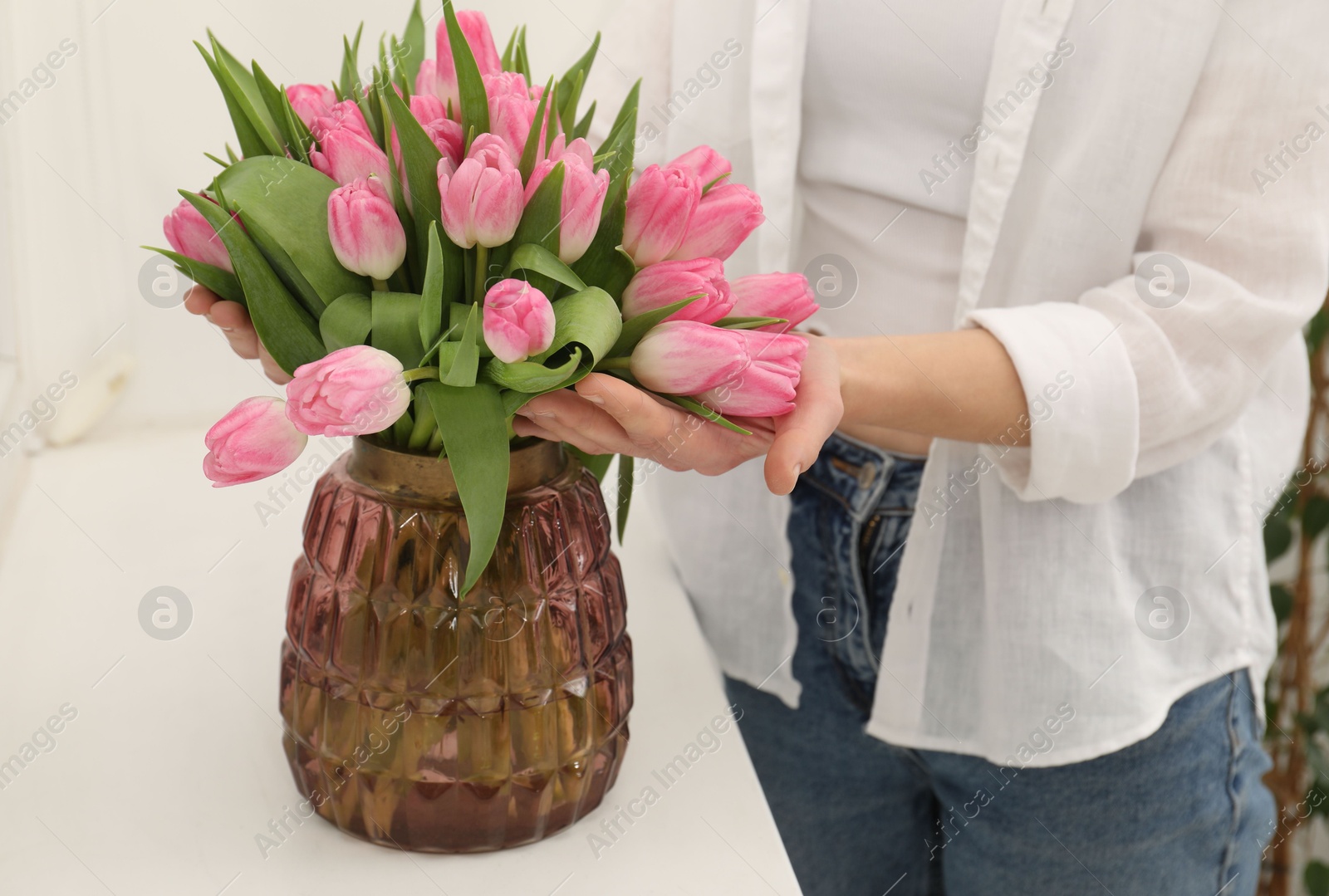 Photo of Woman with bouquet of beautiful tulips near window sill indoors, closeup