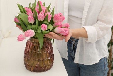 Photo of Woman with bouquet of beautiful tulips near window sill indoors, closeup