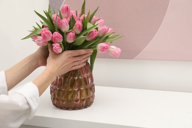 Photo of Woman with bouquet of beautiful tulips near window sill indoors, closeup. Space for text