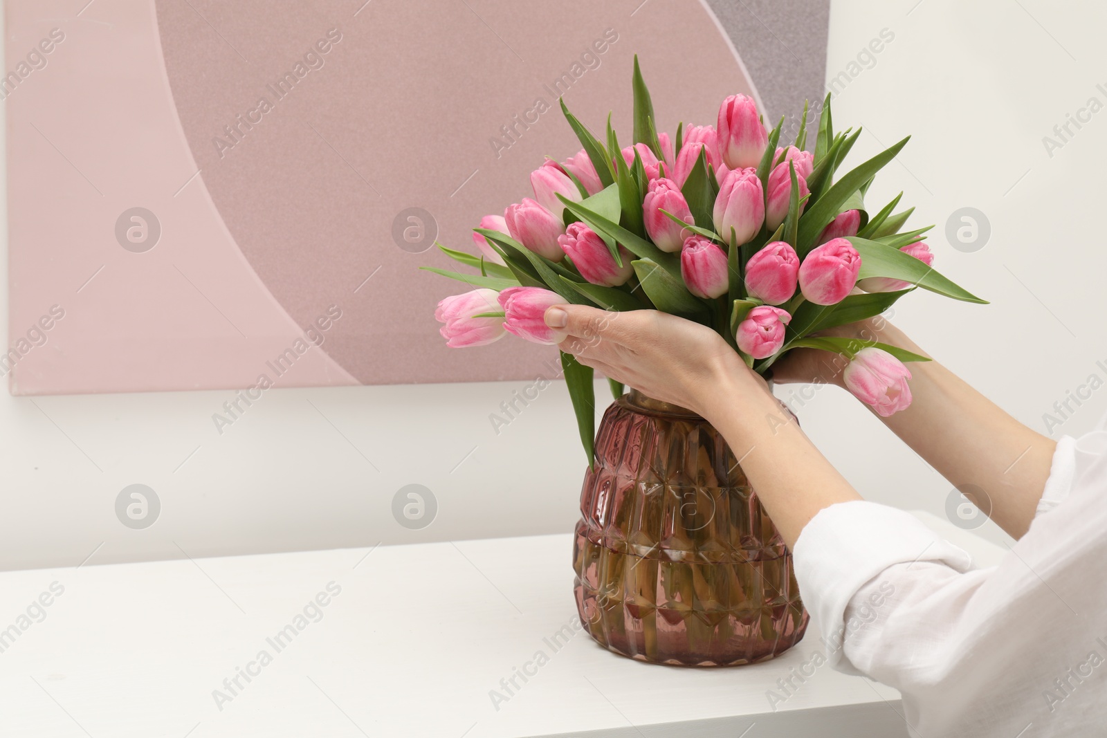 Photo of Woman with bouquet of beautiful tulips near window sill indoors, closeup. Space for text