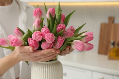 Photo of Woman with bouquet of beautiful tulips in kitchen, closeup