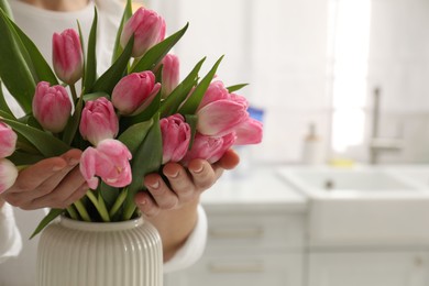 Photo of Woman with bouquet of beautiful tulips in kitchen, closeup. Space for text