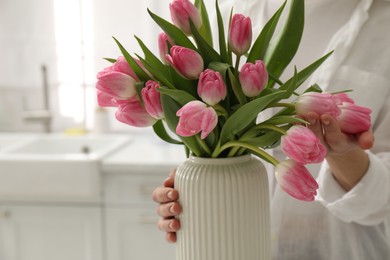 Photo of Woman with bouquet of beautiful tulips in kitchen, closeup