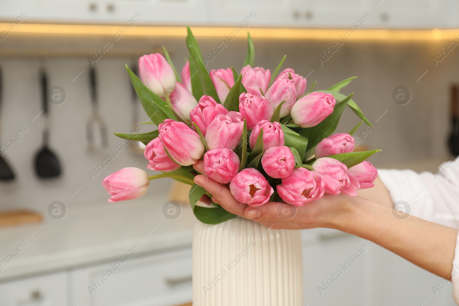 Photo of Woman with bouquet of beautiful tulips in kitchen, closeup