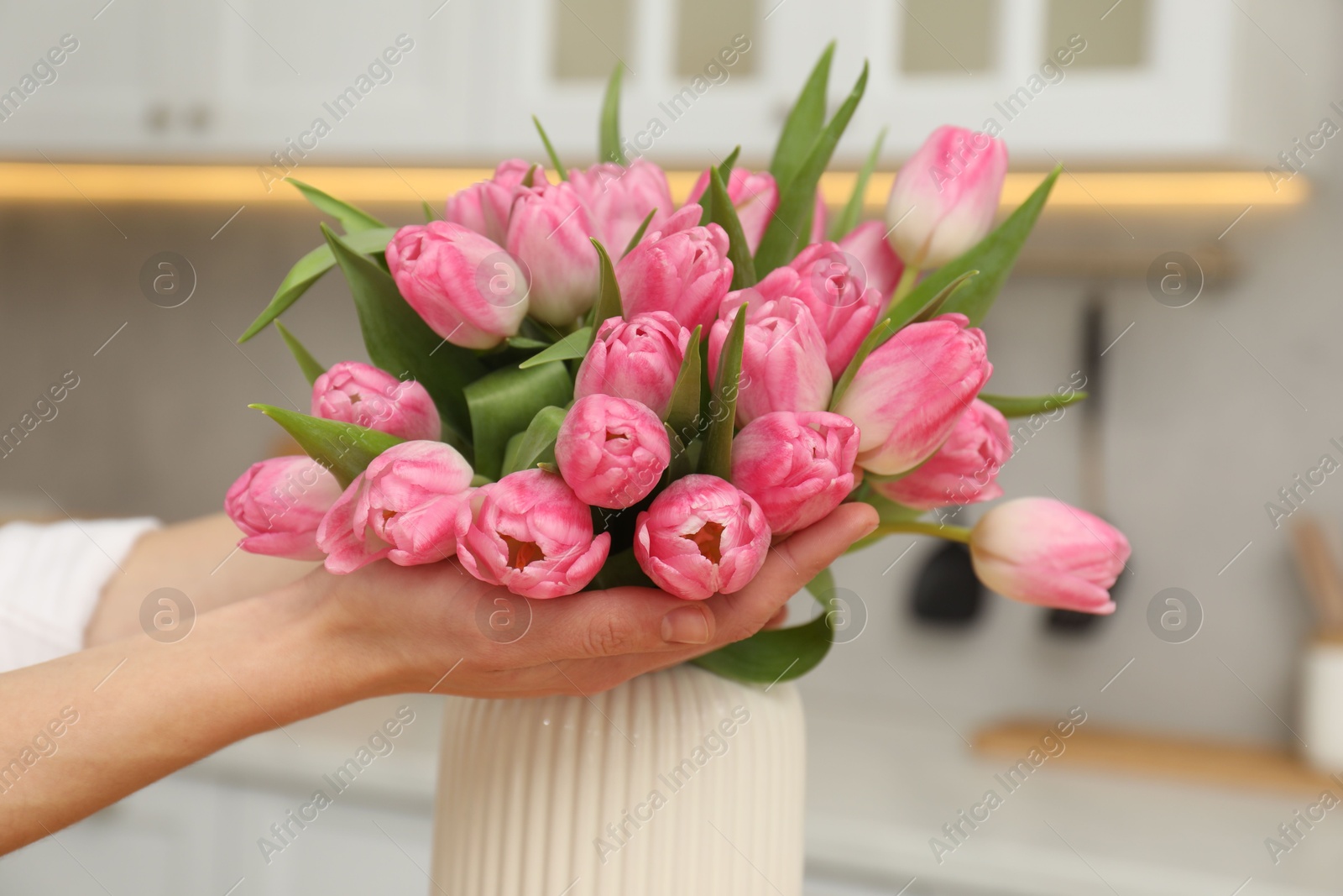 Photo of Woman with bouquet of beautiful tulips in kitchen, closeup