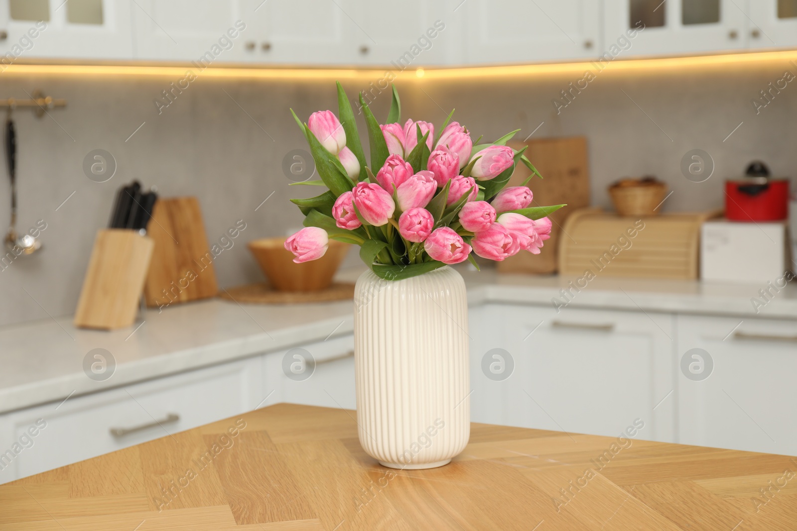 Photo of Bouquet of beautiful tulips in vase on wooden table indoors