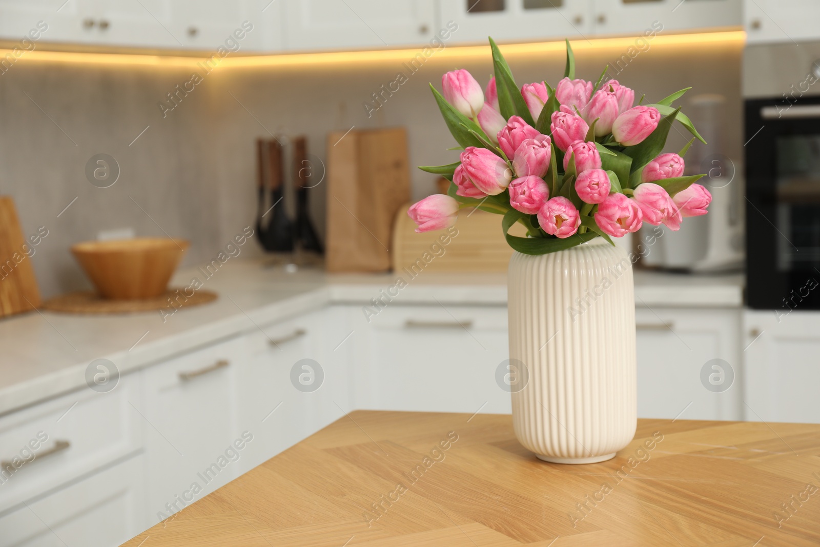 Photo of Bouquet of beautiful tulips in vase on wooden table indoors, space for text