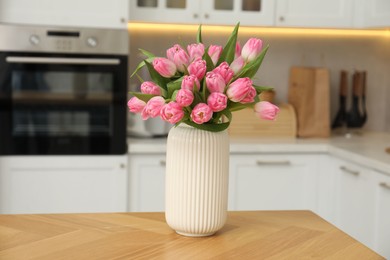 Photo of Bouquet of beautiful tulips in vase on wooden table indoors