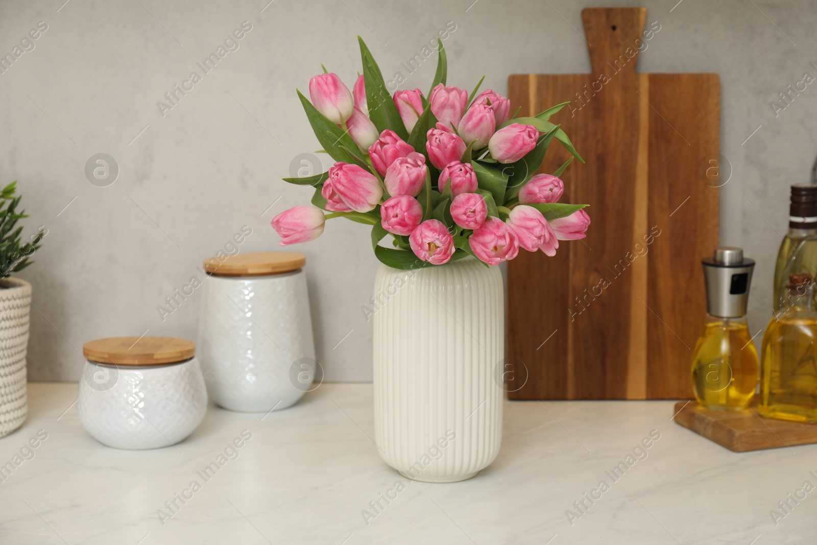 Photo of Bouquet of beautiful tulips in vase on white marble countertop indoors