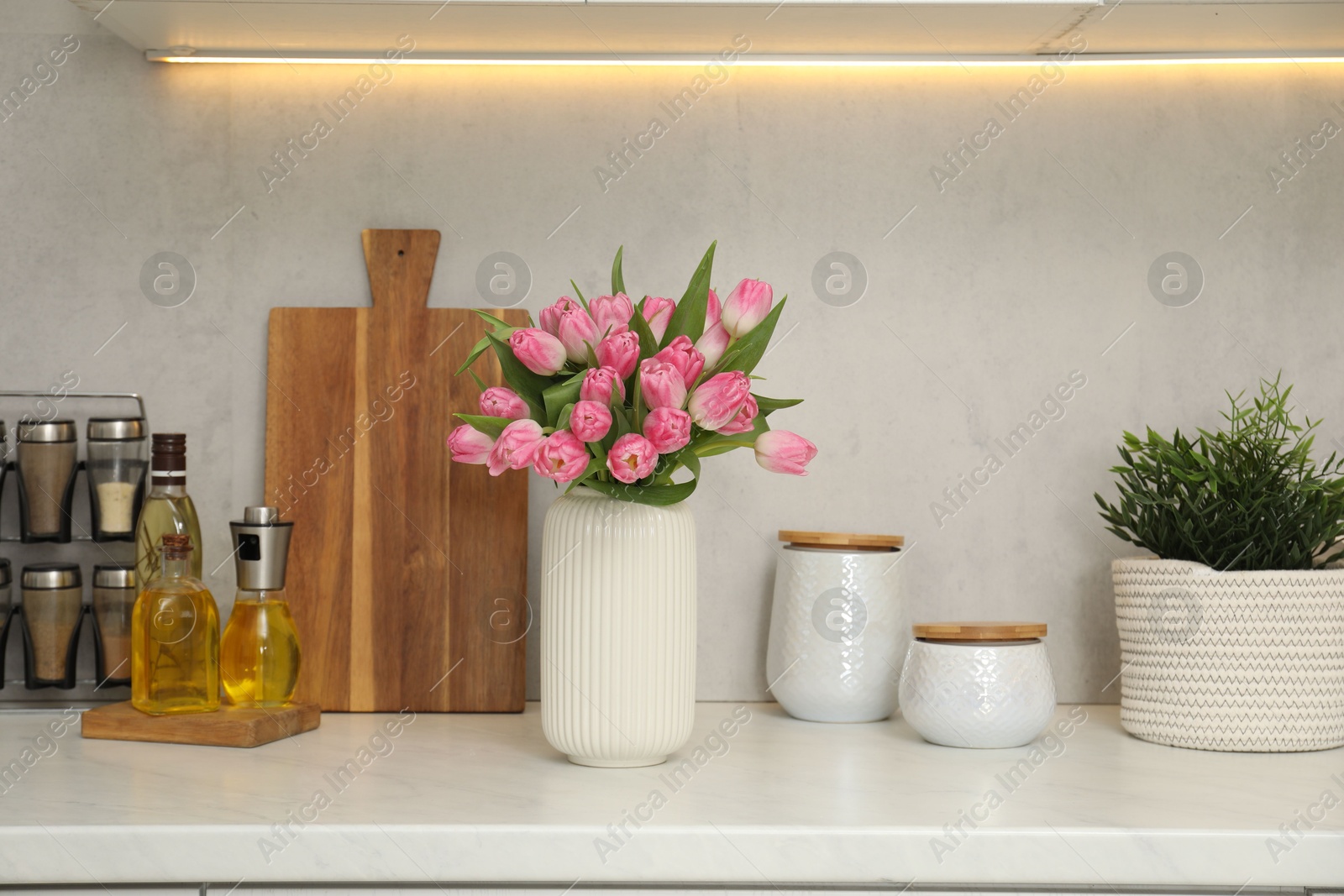 Photo of Bouquet of beautiful tulips in vase on white marble countertop indoors