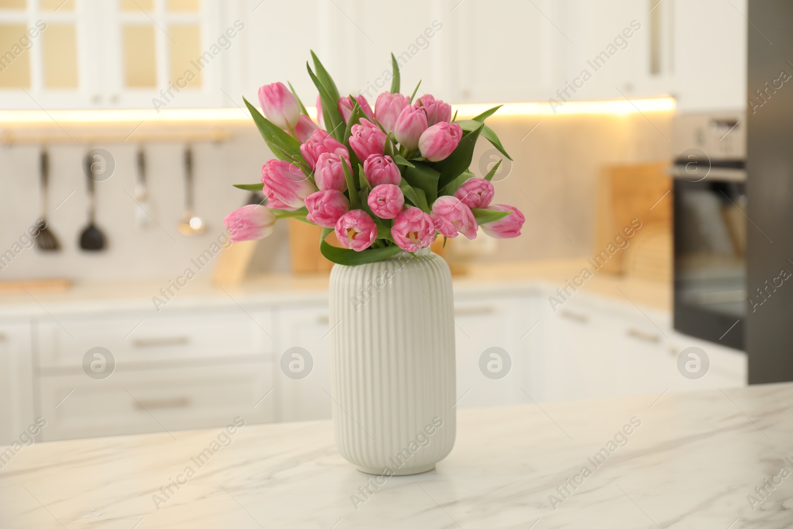 Photo of Bouquet of beautiful tulips in vase on white marble table indoors