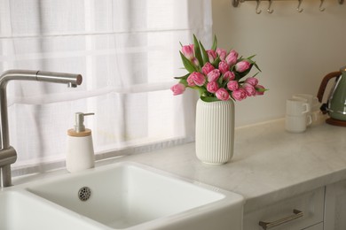 Photo of Bouquet of beautiful tulips in vase on white marble countertop indoors