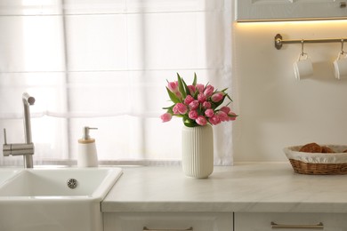 Photo of Bouquet of beautiful tulips in vase on white marble countertop indoors