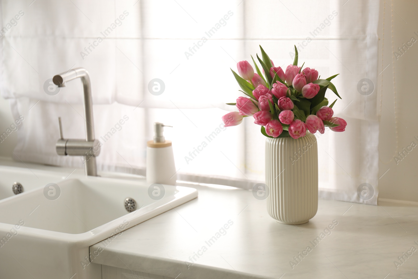 Photo of Bouquet of beautiful tulips in vase on white marble countertop indoors