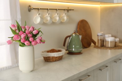 Photo of Bouquet of beautiful tulips in vase on white marble countertop indoors