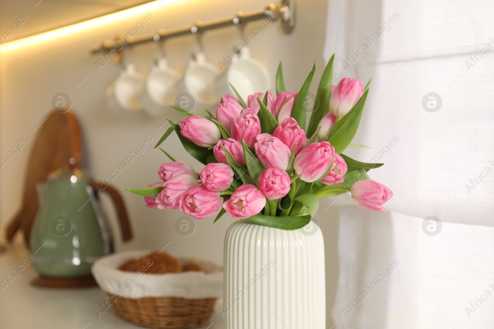 Photo of Bouquet of beautiful tulips in vase on countertop indoors