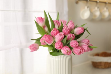 Photo of Bouquet of beautiful tulips in vase on countertop indoors, closeup