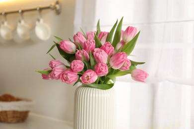 Photo of Bouquet of beautiful tulips in vase on countertop indoors, closeup