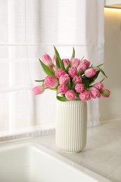 Photo of Bouquet of beautiful tulips in vase on white countertop indoors