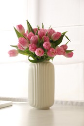 Photo of Bouquet of beautiful tulips in vase on white countertop indoors