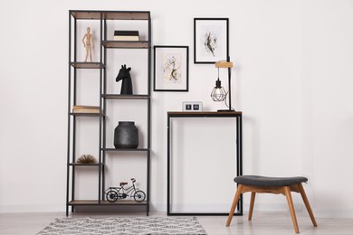 Photo of Shelving unit with different home decor and chair near white wall indoors