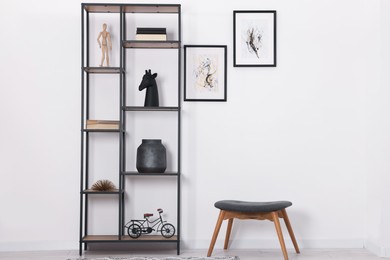 Photo of Shelving unit with different home decor and chair near white wall indoors