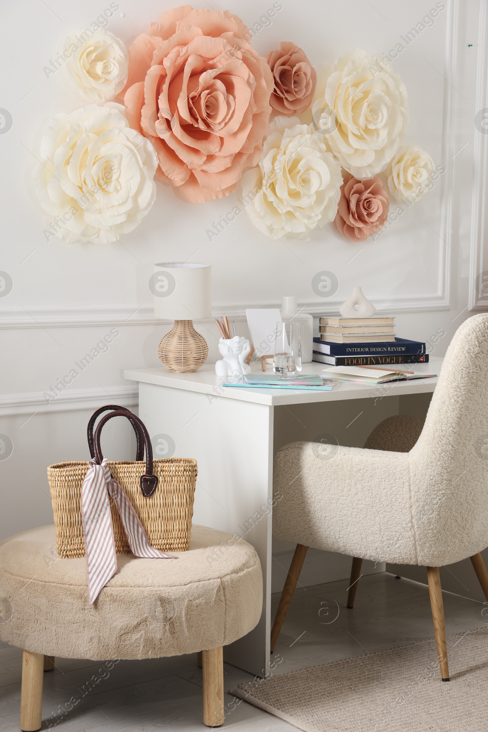 Photo of Beautiful decorative paper flowers on white wall and stylish furniture indoors