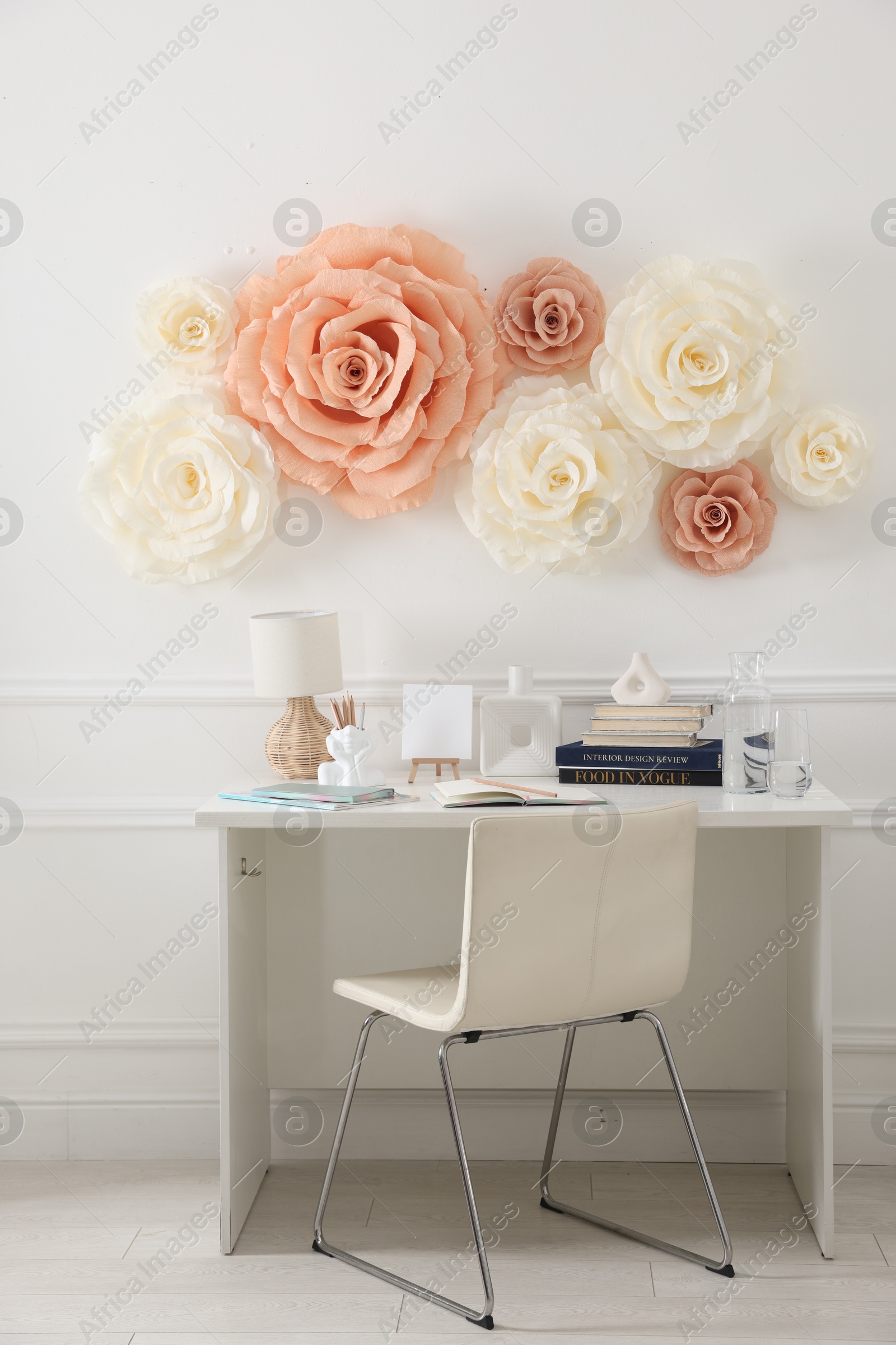 Photo of Beautiful decorative paper flowers on white wall and stylish furniture indoors