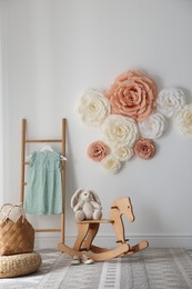 Beautiful decorative paper flowers on white wall in child's room