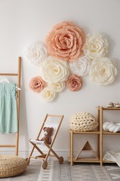 Photo of Beautiful decorative paper flowers on white wall in child's room