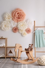 Photo of Beautiful decorative paper flowers on white wall in child's room