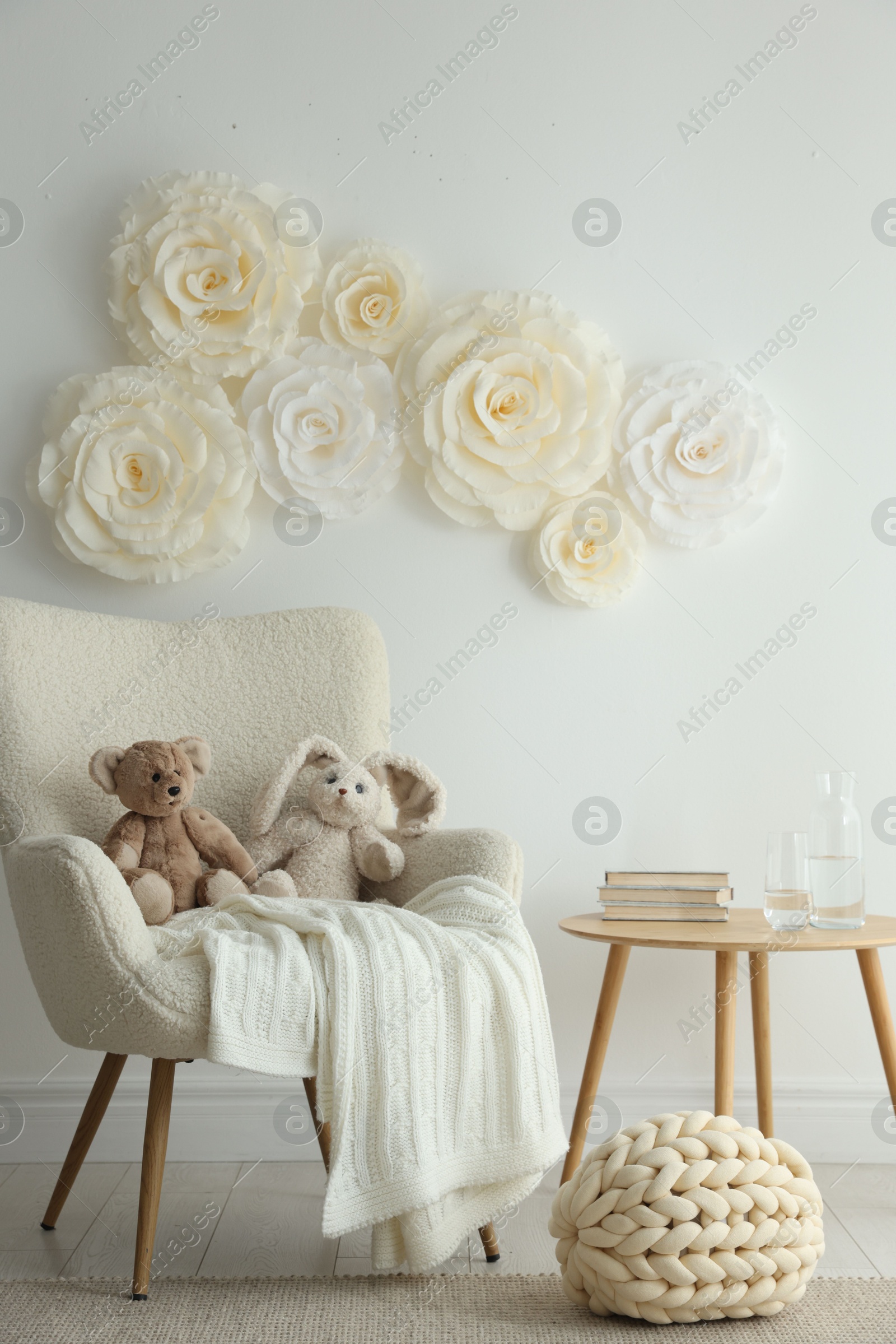 Photo of Beautiful decorative paper flowers on white wall and stylish furniture indoors