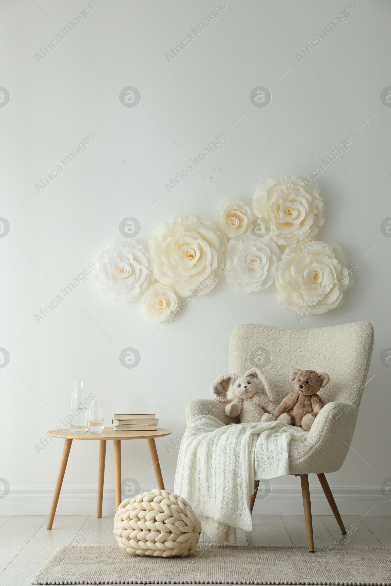 Photo of Beautiful decorative paper flowers on white wall and stylish furniture indoors