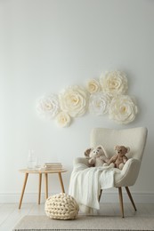 Photo of Beautiful decorative paper flowers on white wall and stylish furniture indoors