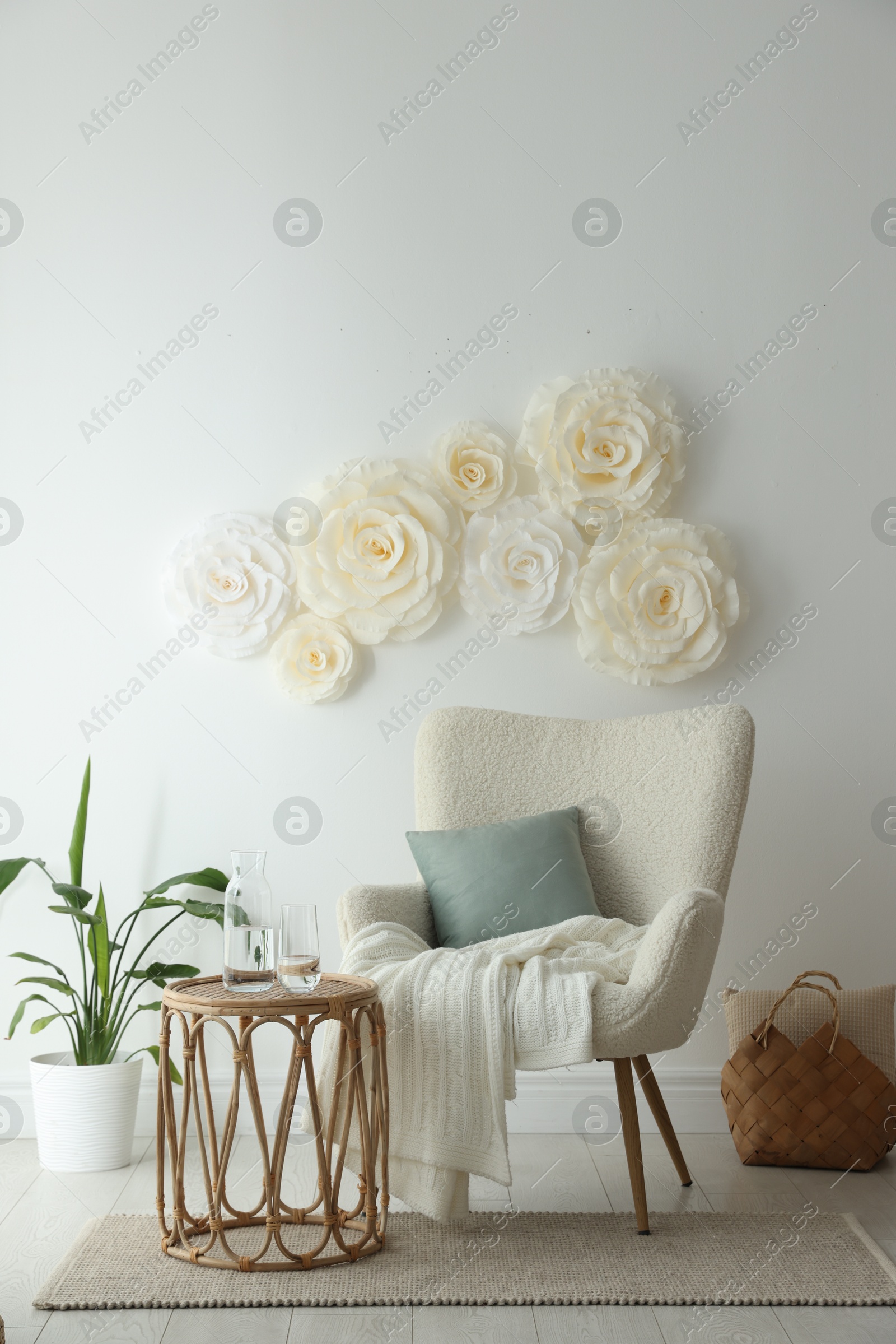 Photo of Beautiful decorative paper flowers on white wall and stylish furniture indoors