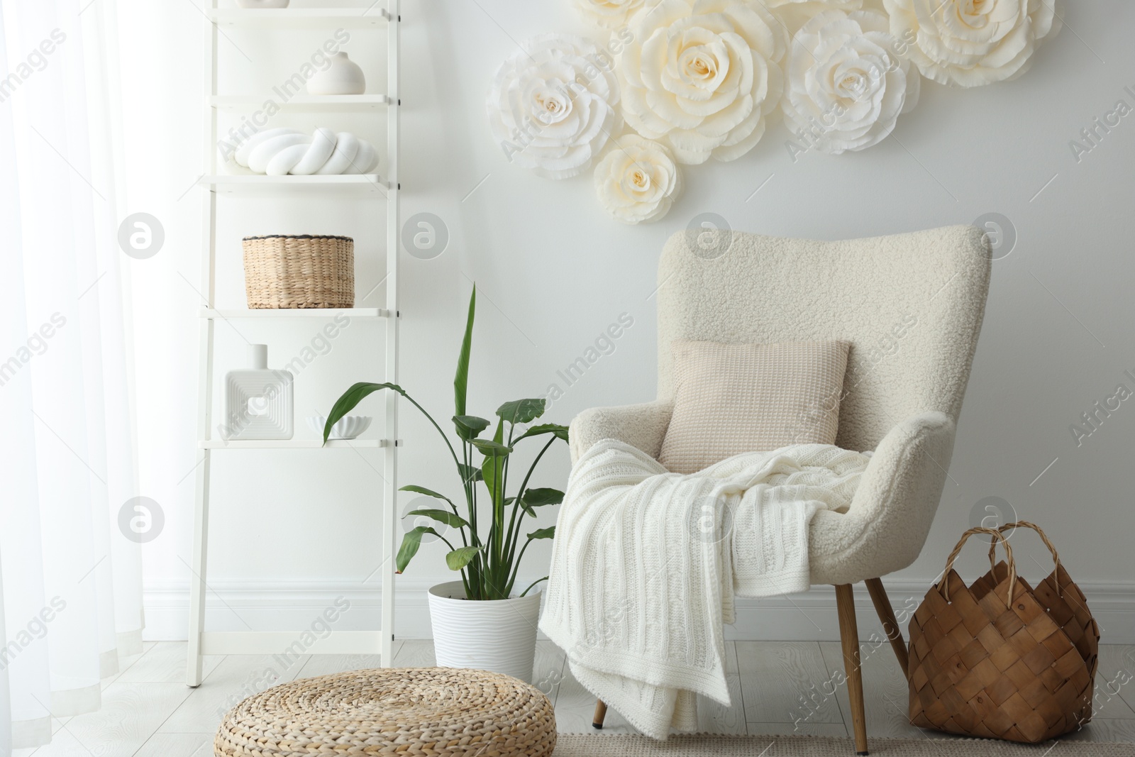 Photo of Beautiful decorative paper flowers on white wall and stylish furniture indoors