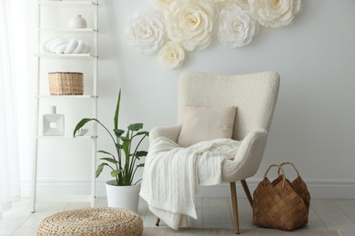 Photo of Beautiful decorative paper flowers on white wall and stylish furniture indoors