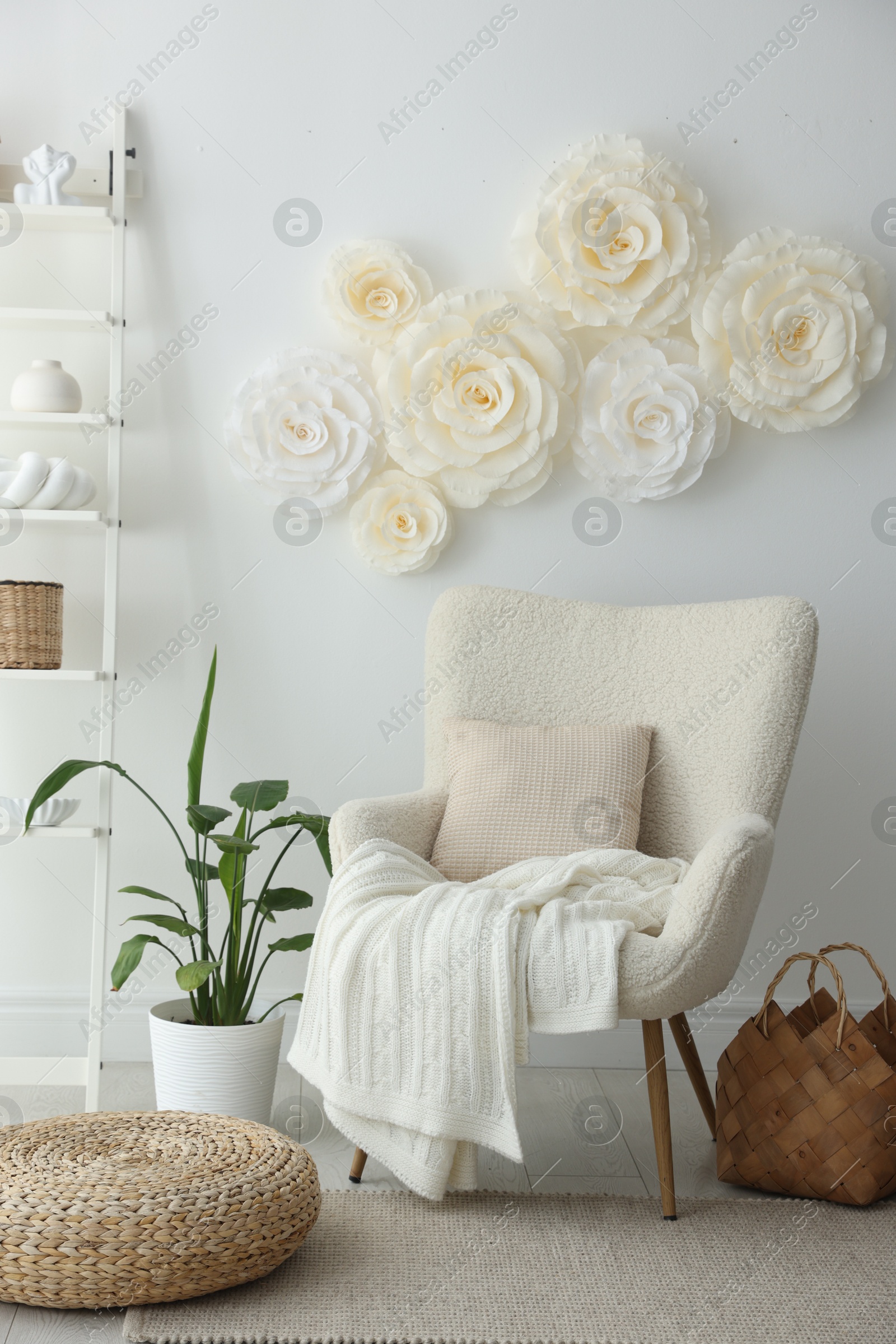 Photo of Beautiful decorative paper flowers on white wall and stylish furniture indoors