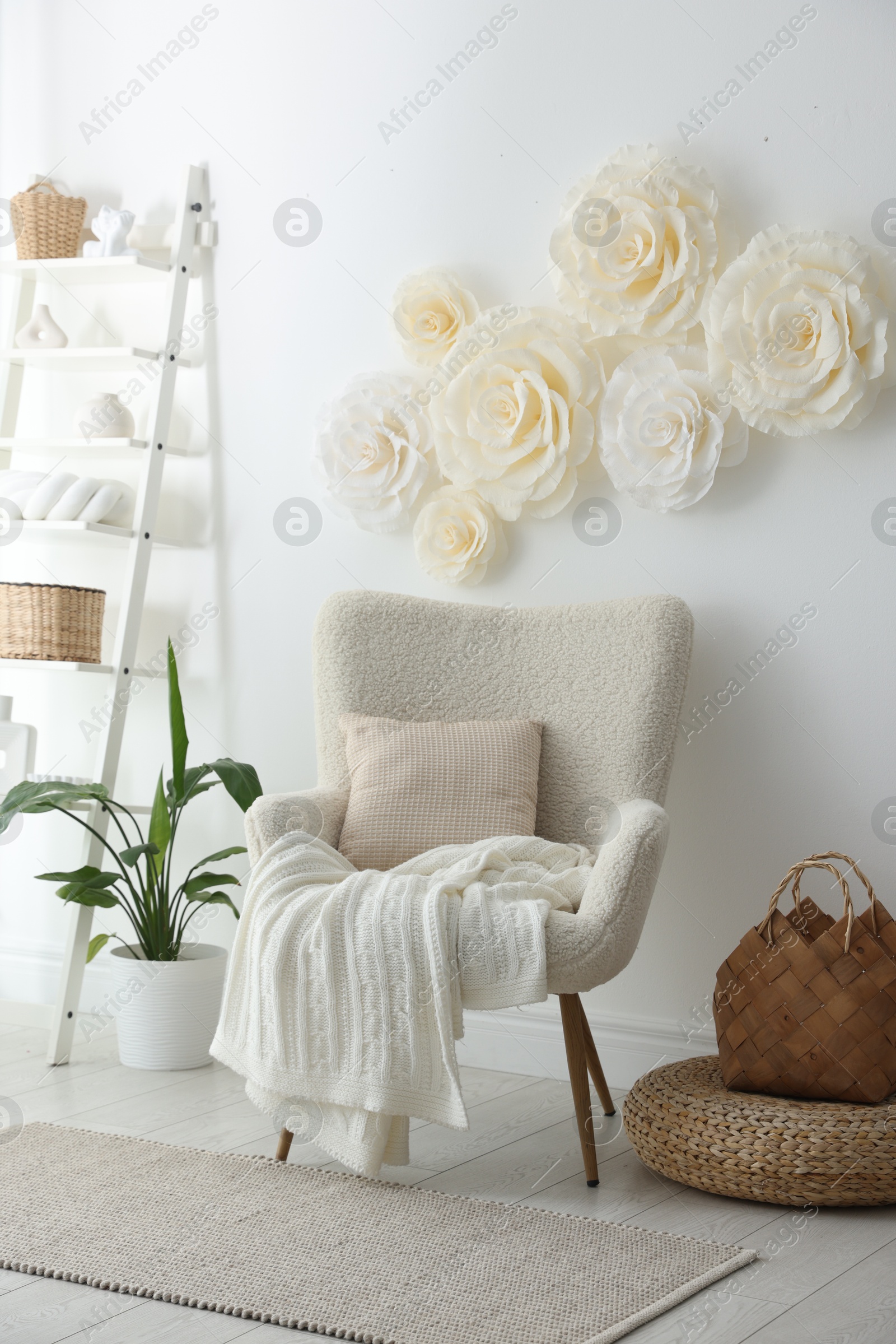 Photo of Beautiful decorative paper flowers on white wall and stylish furniture indoors