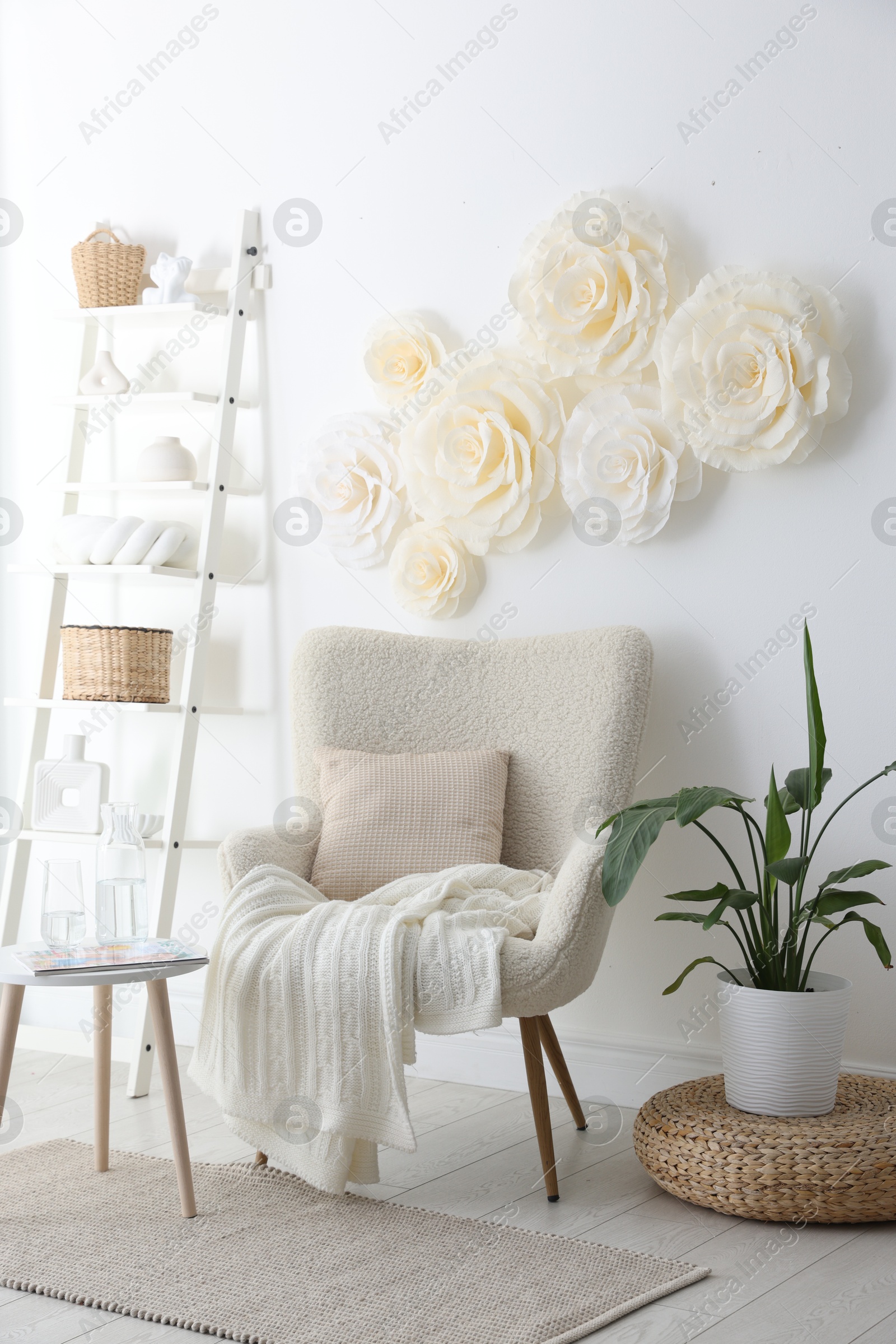 Photo of Beautiful decorative paper flowers on white wall and stylish furniture indoors