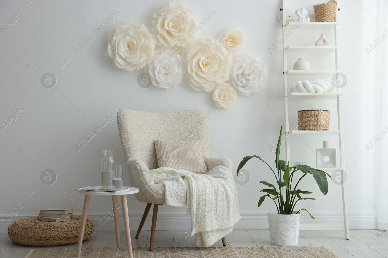 Photo of Beautiful decorative paper flowers on white wall and stylish furniture indoors