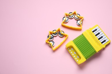 Photo of Bright toy tambourines and accordion on pink background, flat lay. Space for text