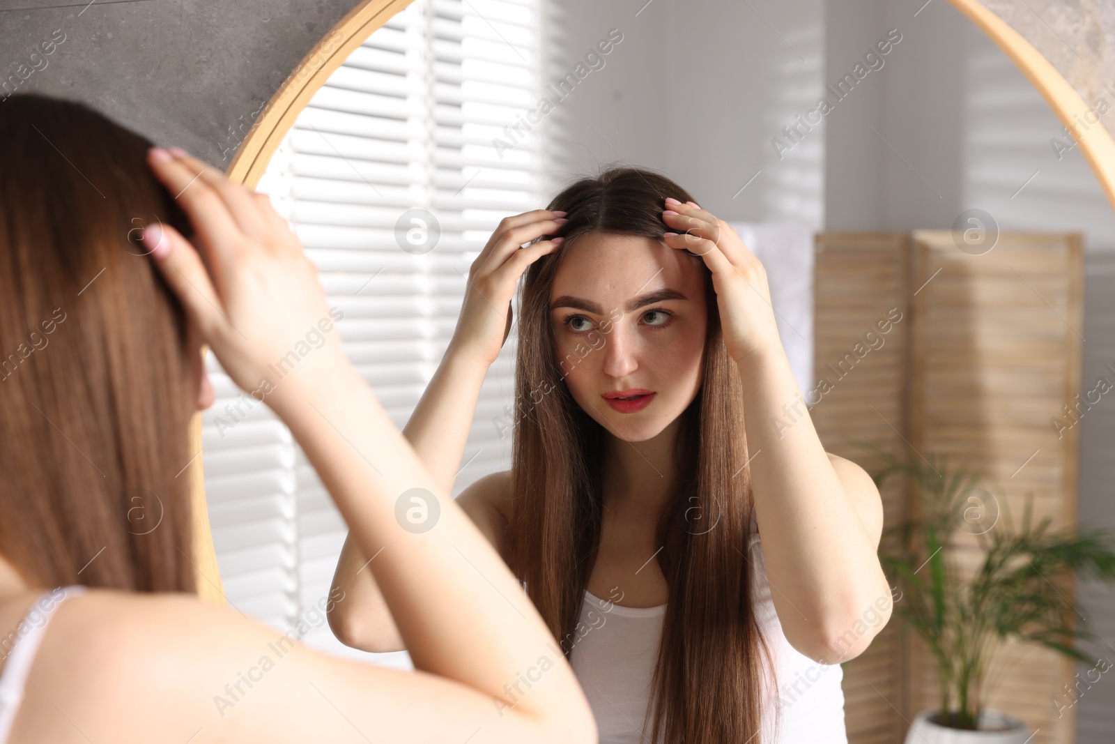 Photo of Beautiful woman with healthy hair roots near mirror at home