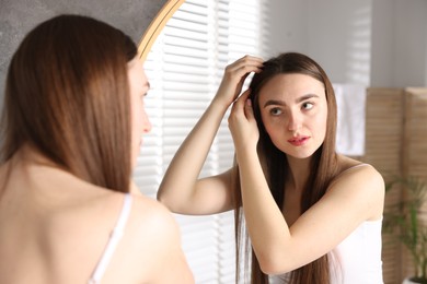 Photo of Beautiful woman with healthy hair roots near mirror at home