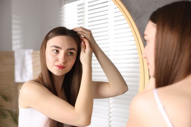 Photo of Beautiful woman with healthy hair roots near mirror at home