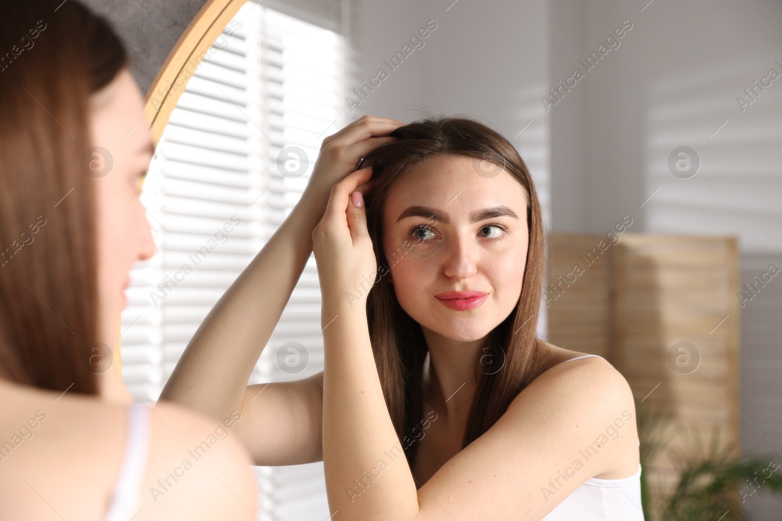 Photo of Beautiful woman with healthy hair roots near mirror at home