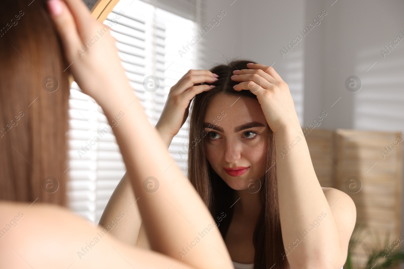 Photo of Beautiful woman with healthy hair roots near mirror at home